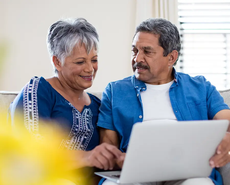Senior couple watching a funeral live stream on their laptop.